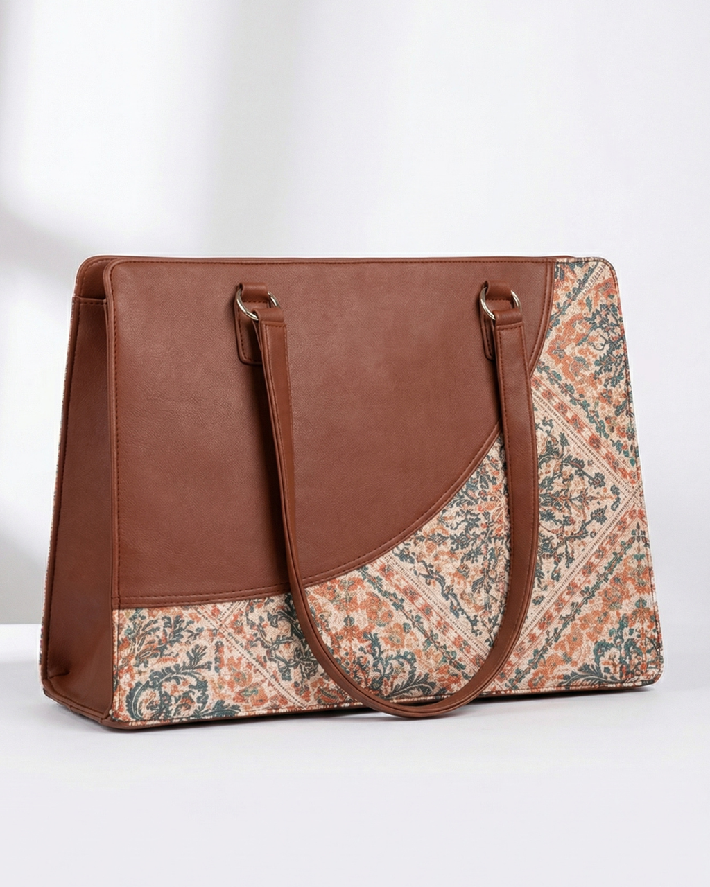 Brown handbag with floral patterned flap on a white background