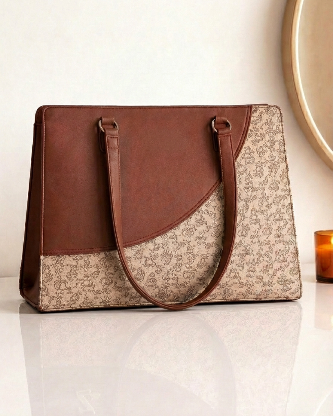 Handbag with brown leather top section and floral patterned fabric base on a white surface.