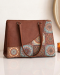Brown leather tote bag with patterned flap on a white surface