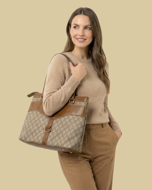 Woman holding a large beige and brown handbag against a beige background