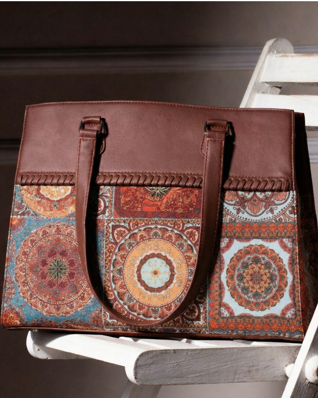 Brown leather handbag with colorful patterned flap on a wooden surface