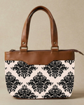 Handbag with black floral pattern on white background and brown leather accents