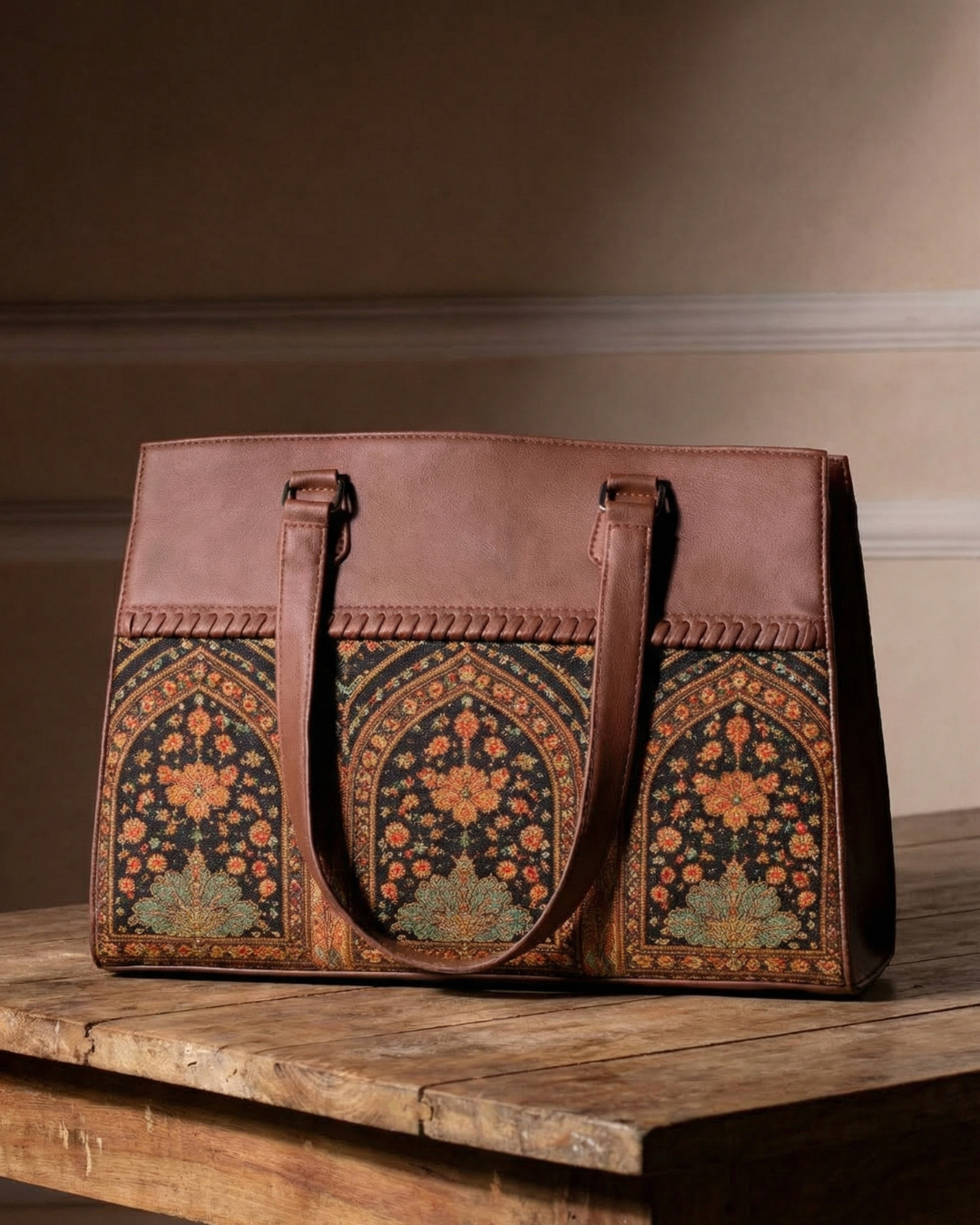 Brown leather bag with intricate floral patterns on a wooden surface