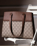 Brown patterned handbag on a white chair with a neutral background