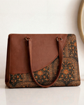 Brown leather handbag with patterned flap on a white surface