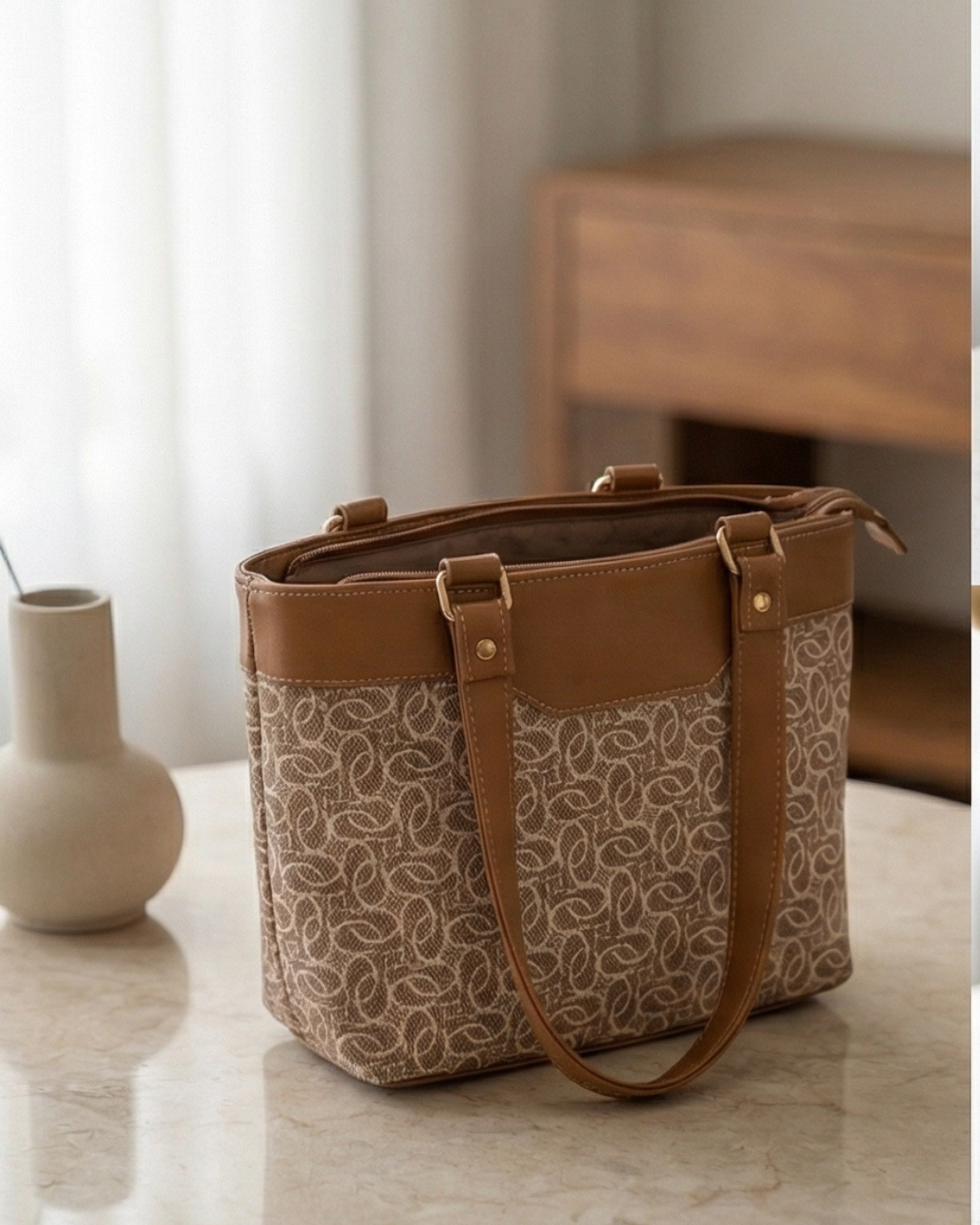 Brown and beige patterned handbag on a light surface with a blurred background