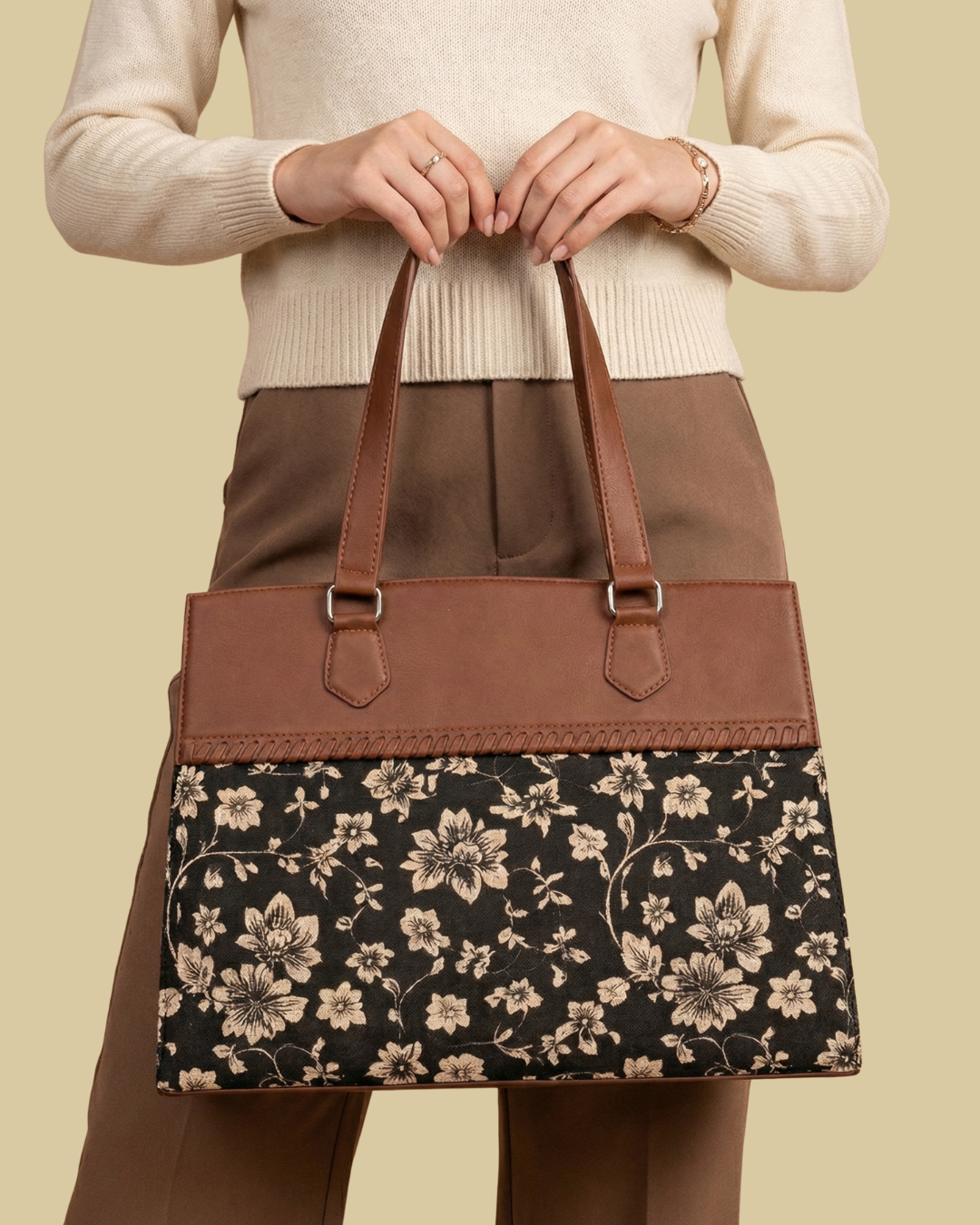 Person holding a floral-patterned handbag with brown leather accents