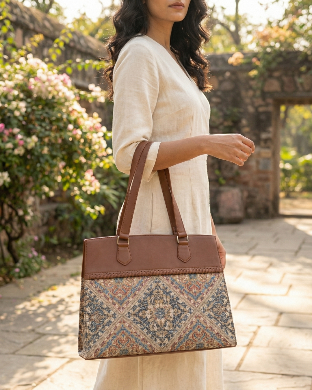Woman holding a brown and patterned handbag in an outdoor setting