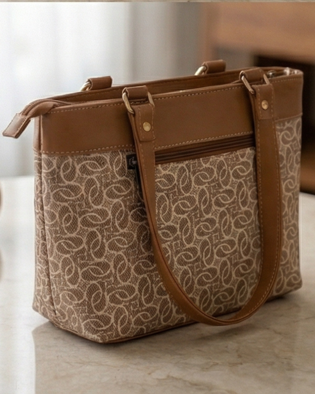 Patterned handbag with brown leather accents on a marble surface