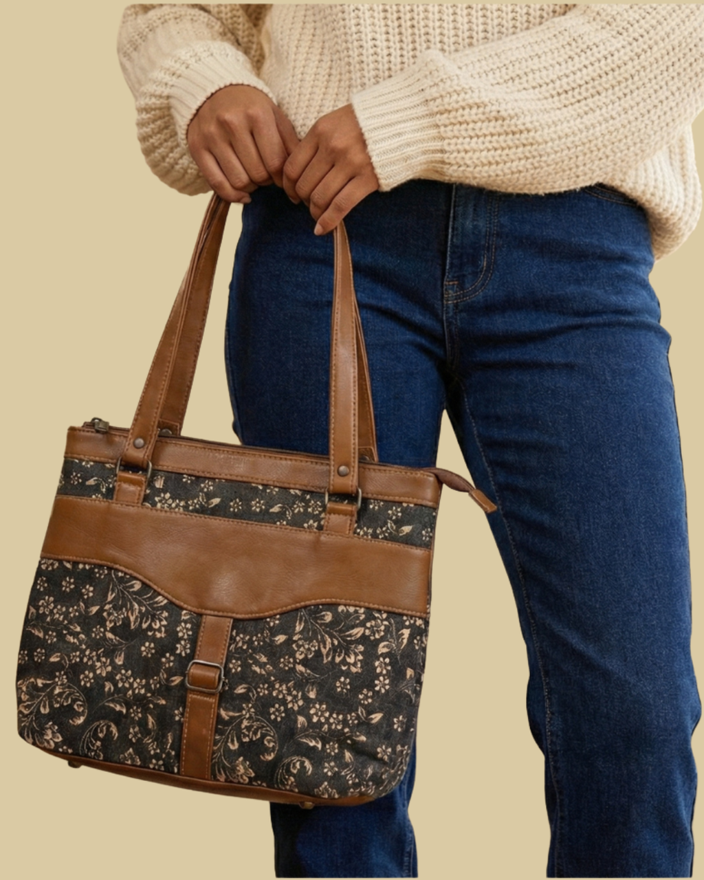 Person holding a floral-patterned handbag with brown leather accents