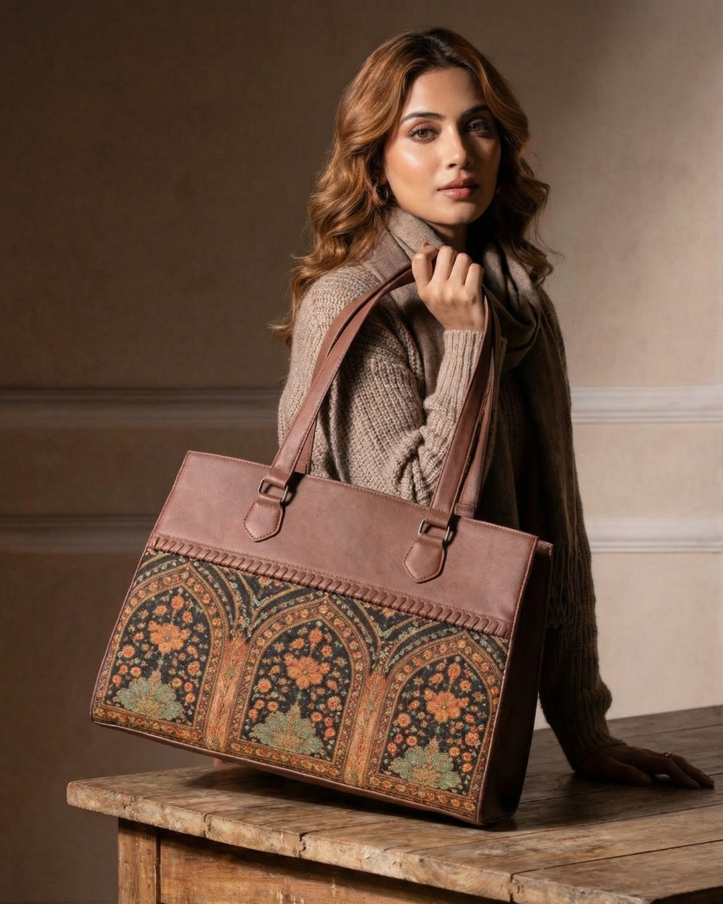 Woman holding a brown leather bag with intricate patterns on a wooden surface.