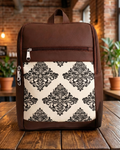 Brown backpack with black floral pattern on a wooden surface