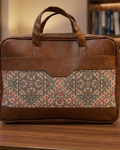 Brown leather briefcase with patterned flap on a wooden surface