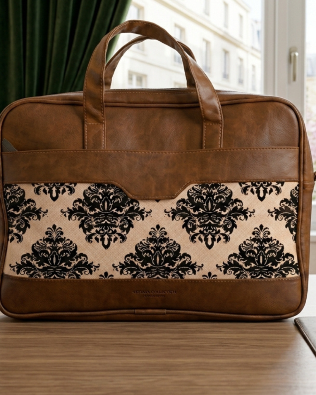 Brown leather briefcase with black floral pattern on a wooden surface